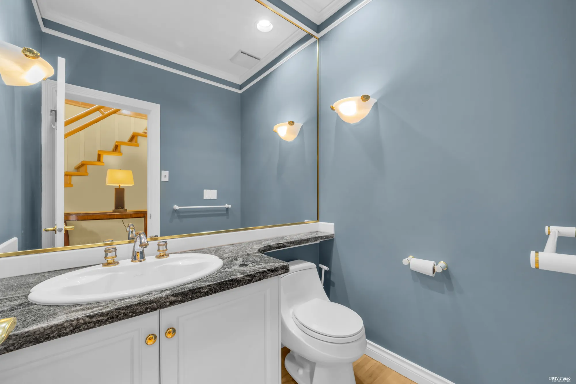 A powder room with a granite counter and blue walls