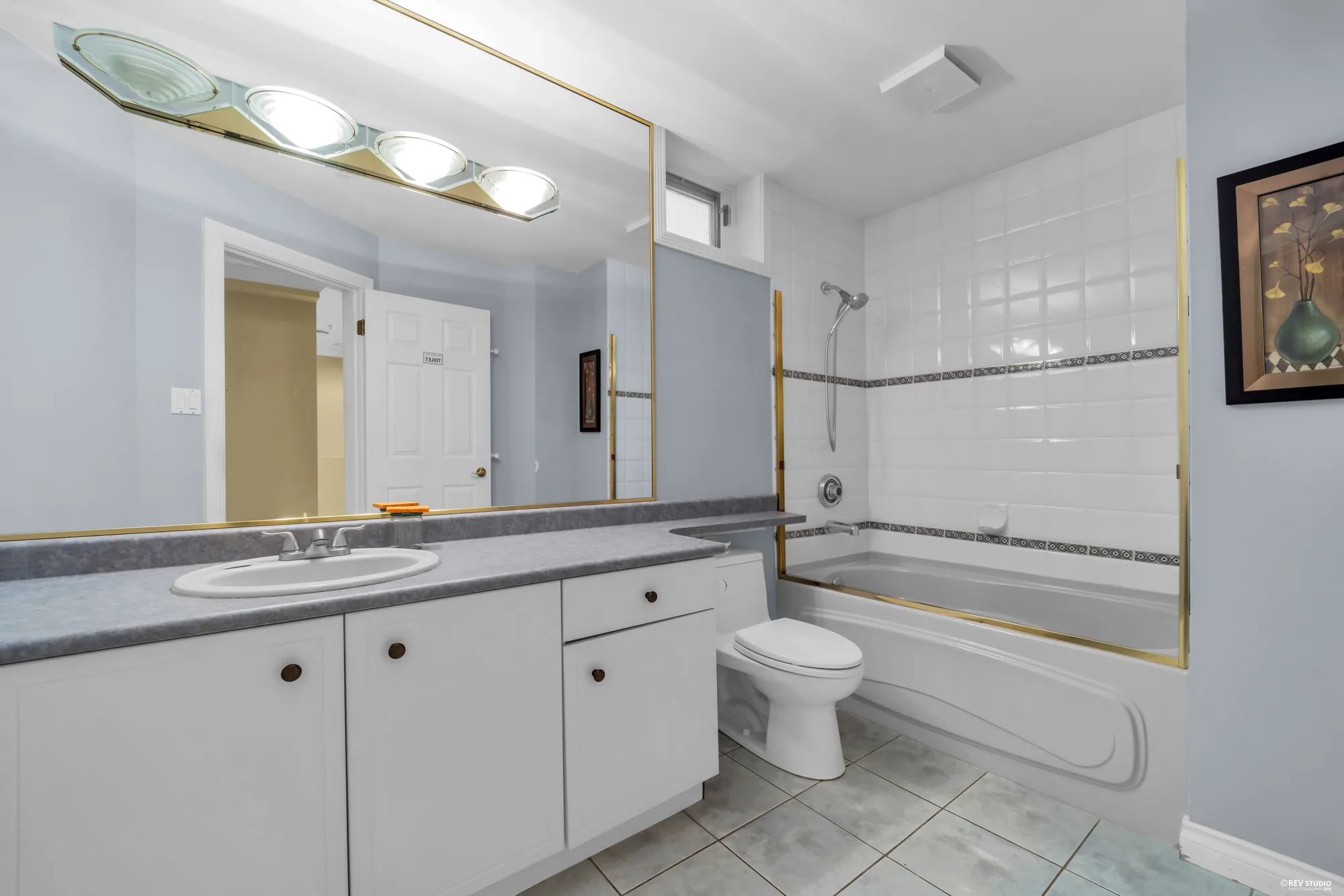 A bathroom with a tub, a long vanity and a mirrored wall