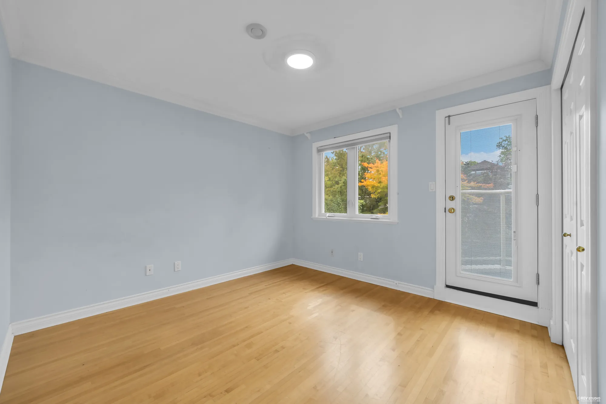 A bedroom with two windows and a hardwood floor