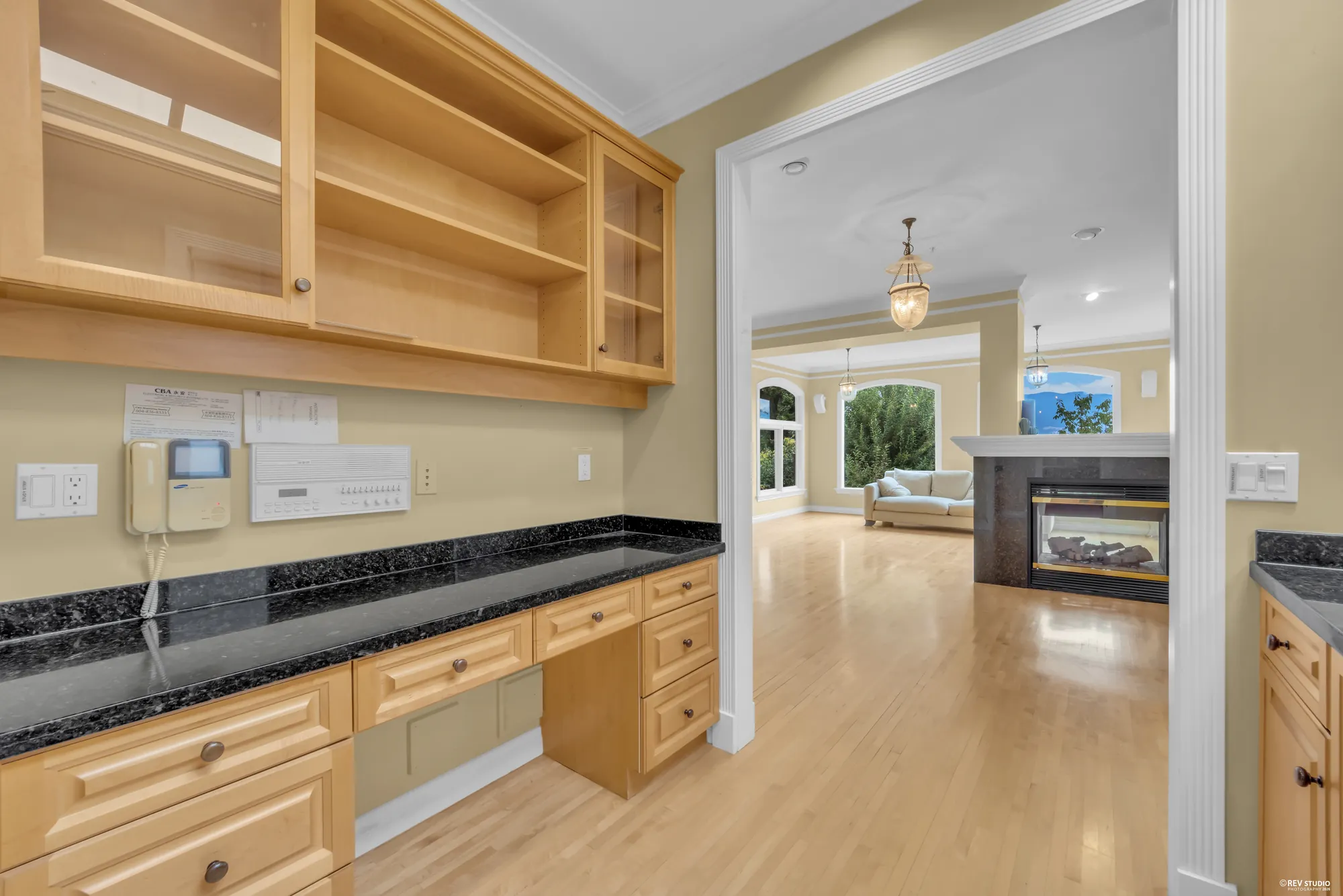 A built-in desk and cabinetry along one wall with the kitchen beyond