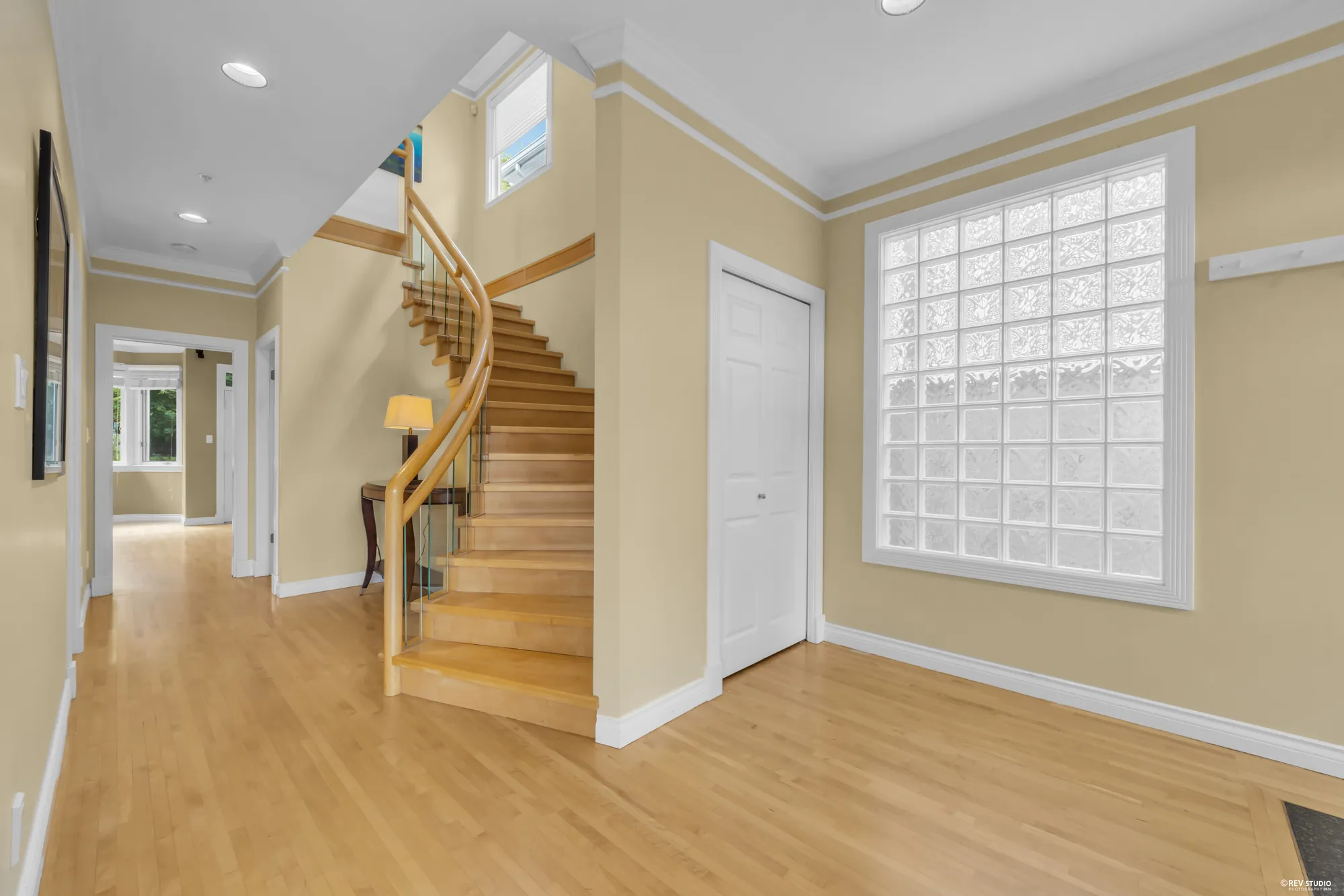 The entrance hall with a curved staircase and glass block window