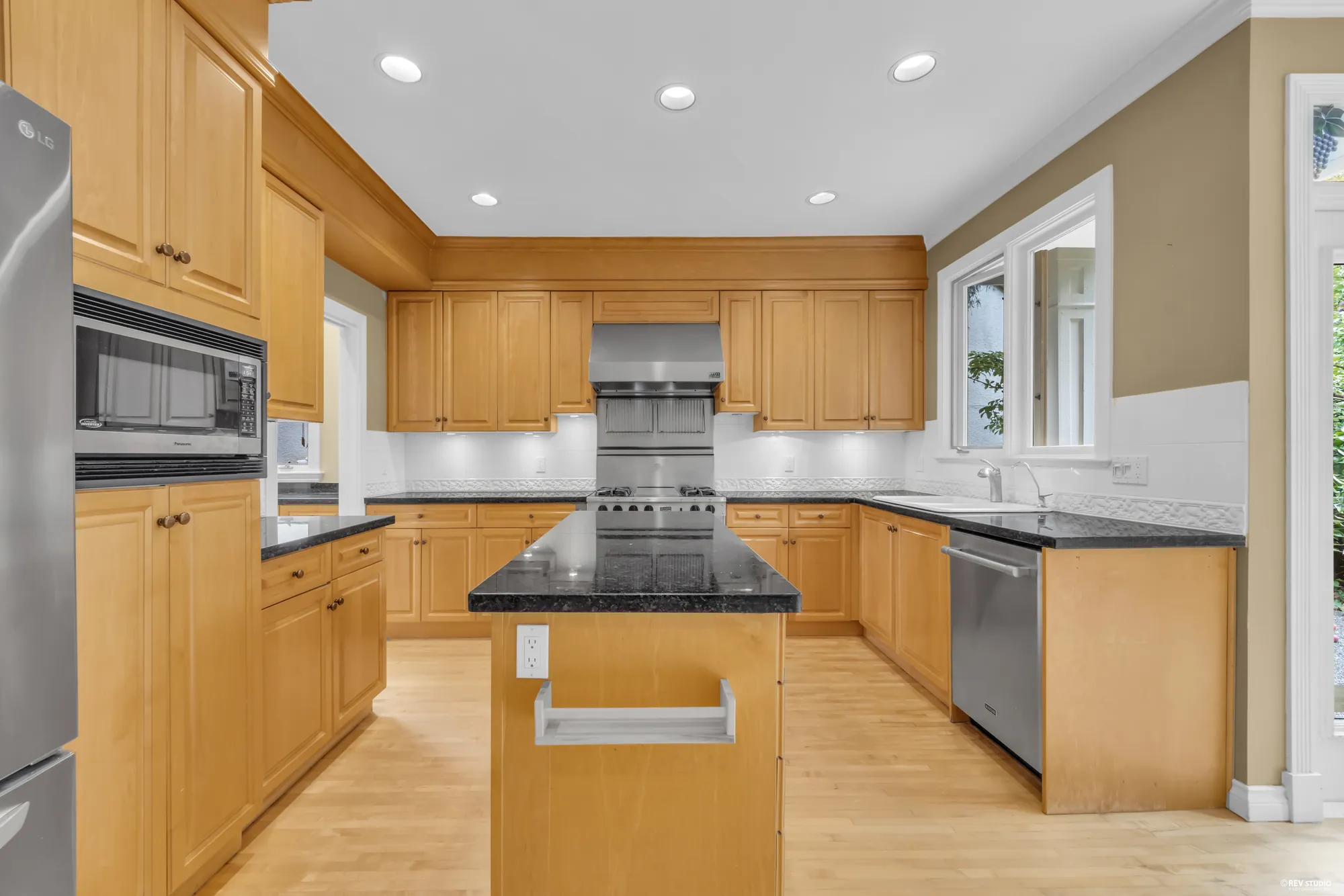 The kitchen with maple cabinets, a granite island and stainless appliances