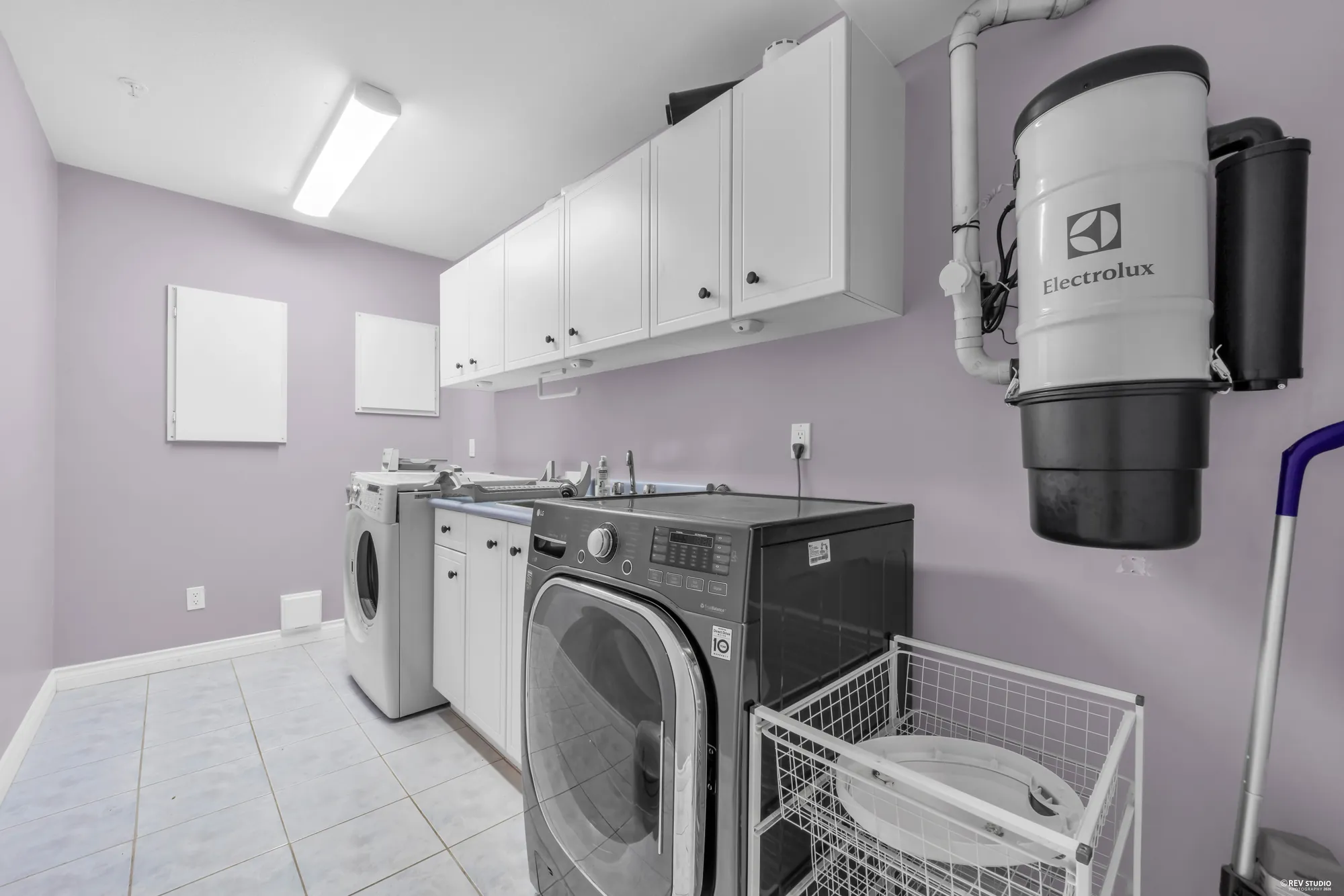 The laundry room with a washer, dryer, sink and built-in vacuum