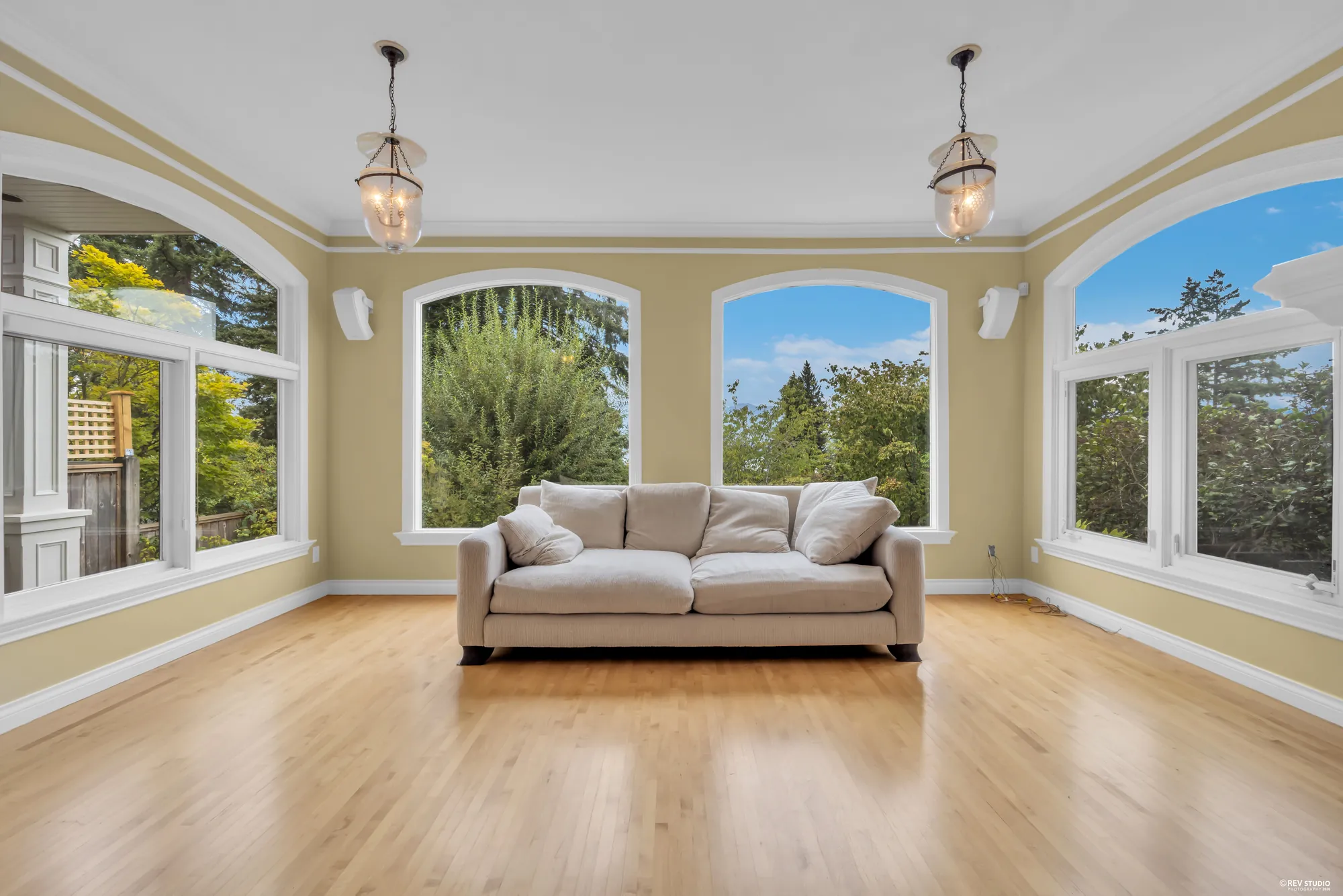 The living room with arched windows on two walls and a hardwood floor