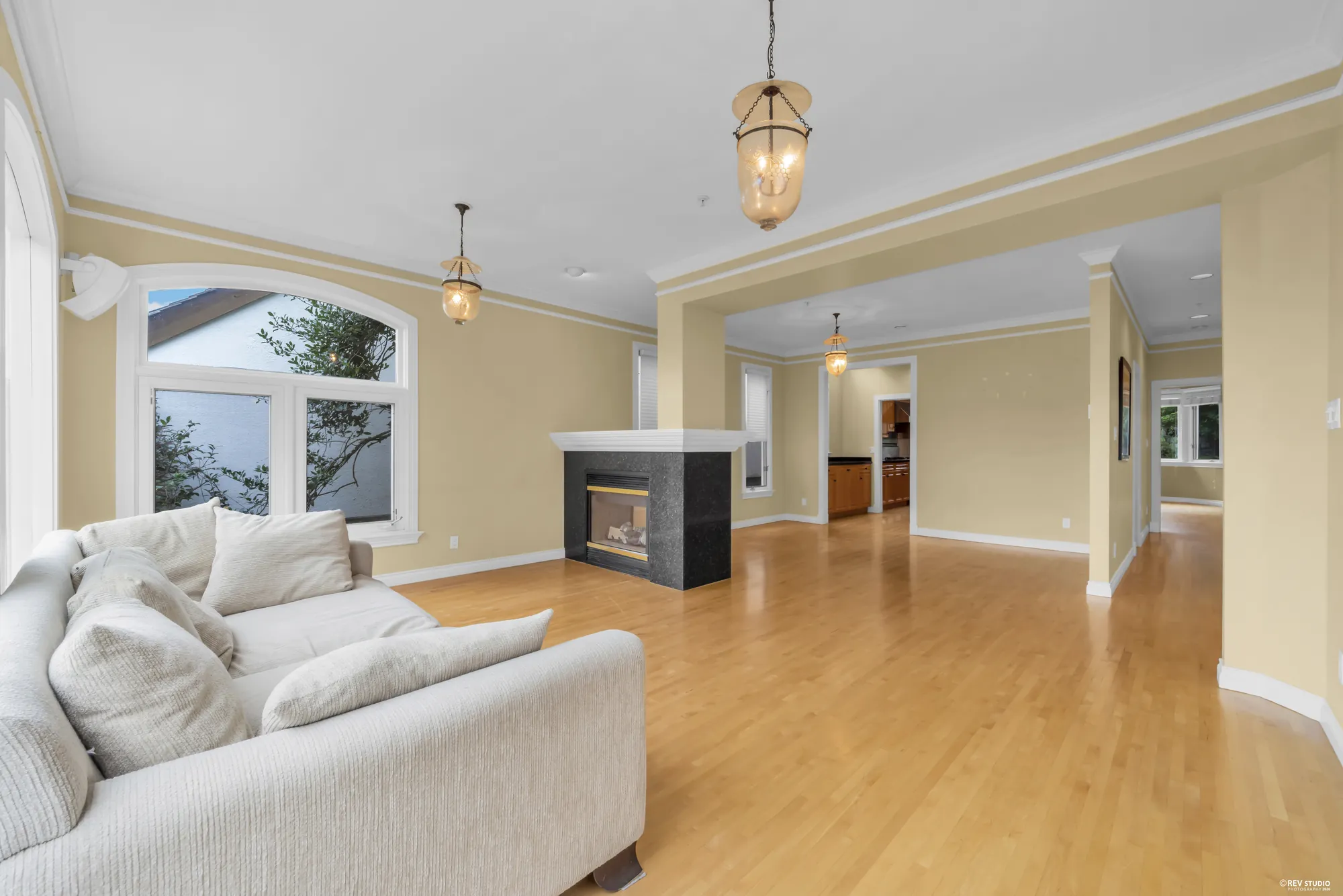 An open living area with a double-sided fireplace and a hallway beyond