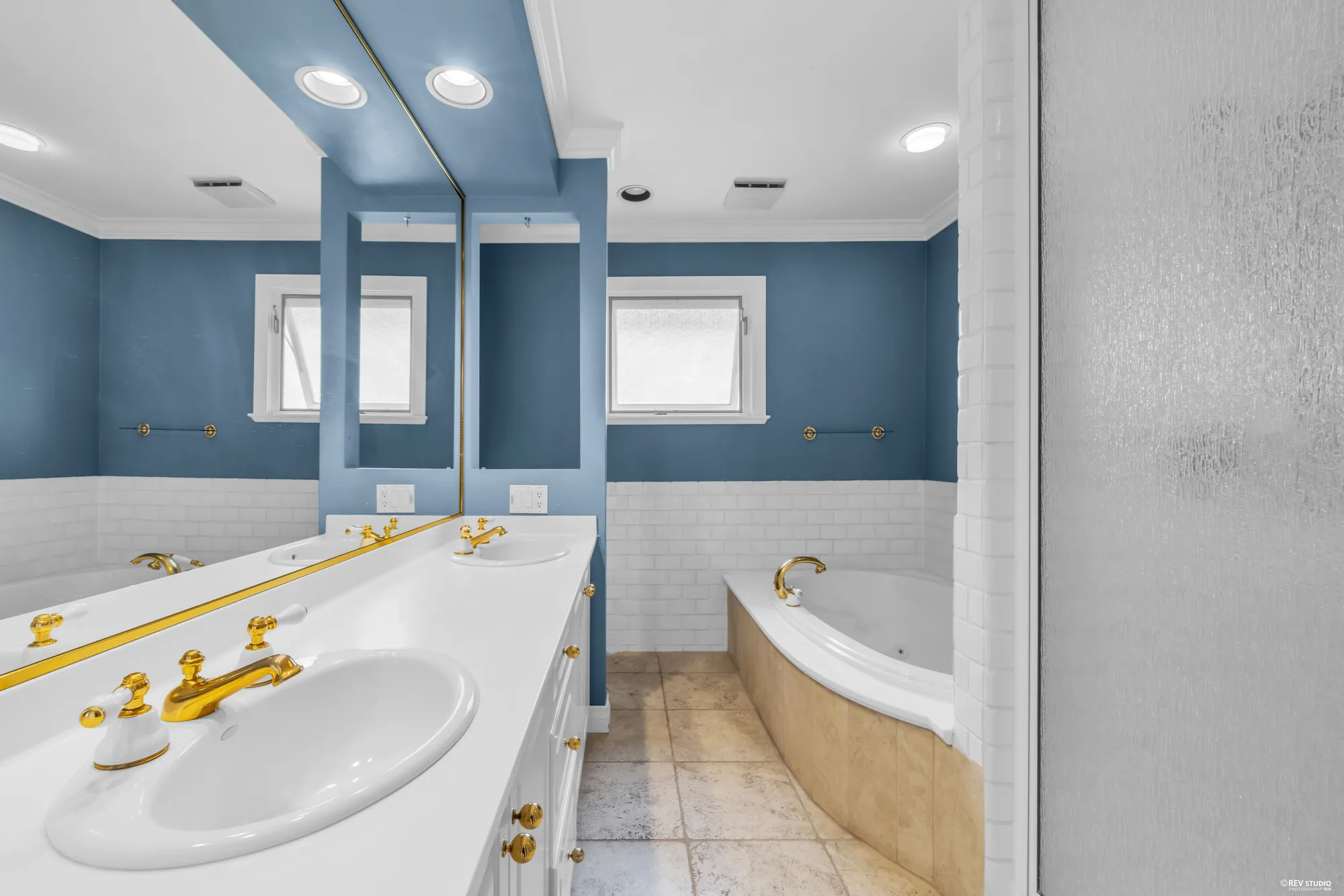 The primary bathroom with a corner tub, twin basins and blue walls