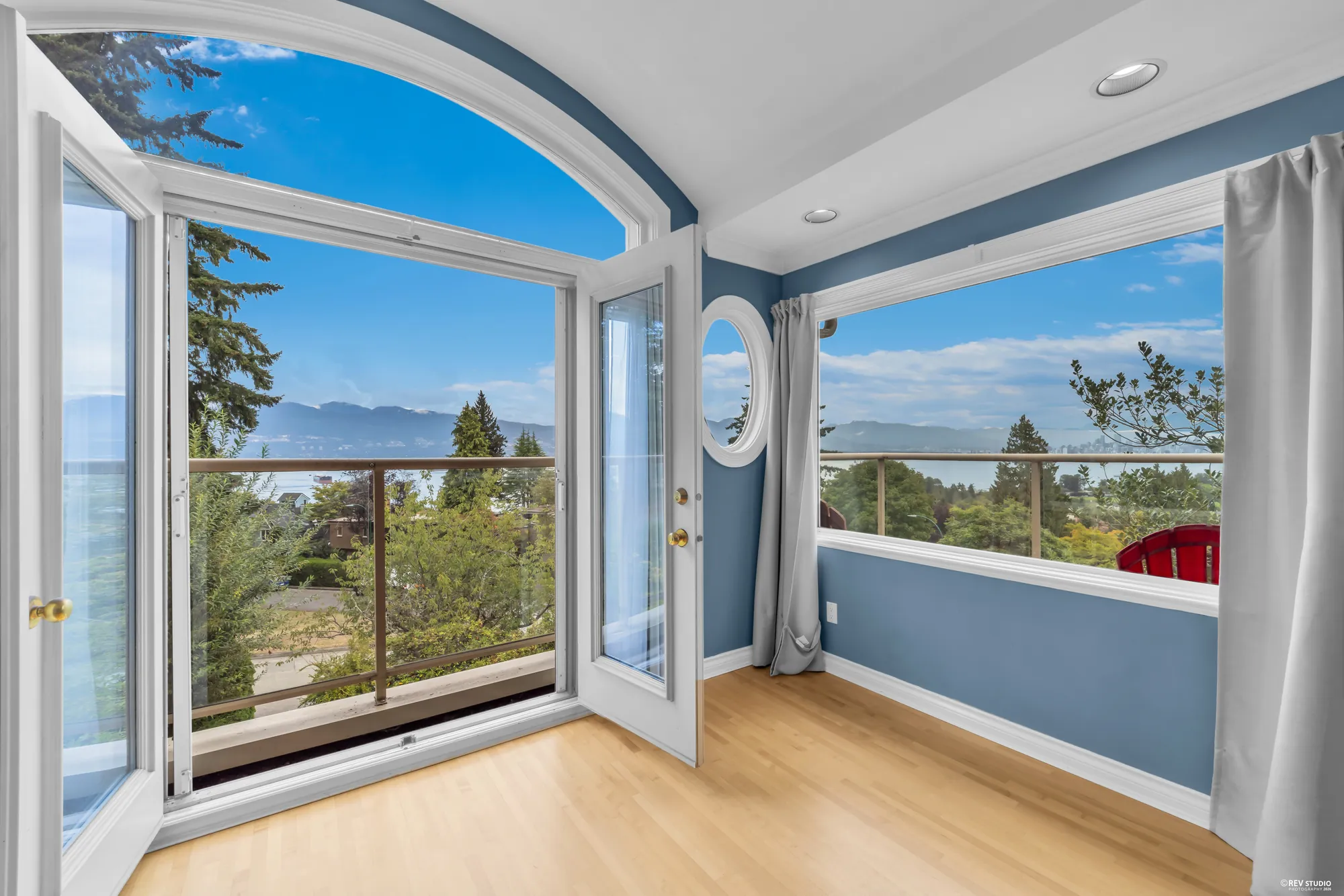 The arched window of the primary bedroom open onto the balcony, with the water beyond