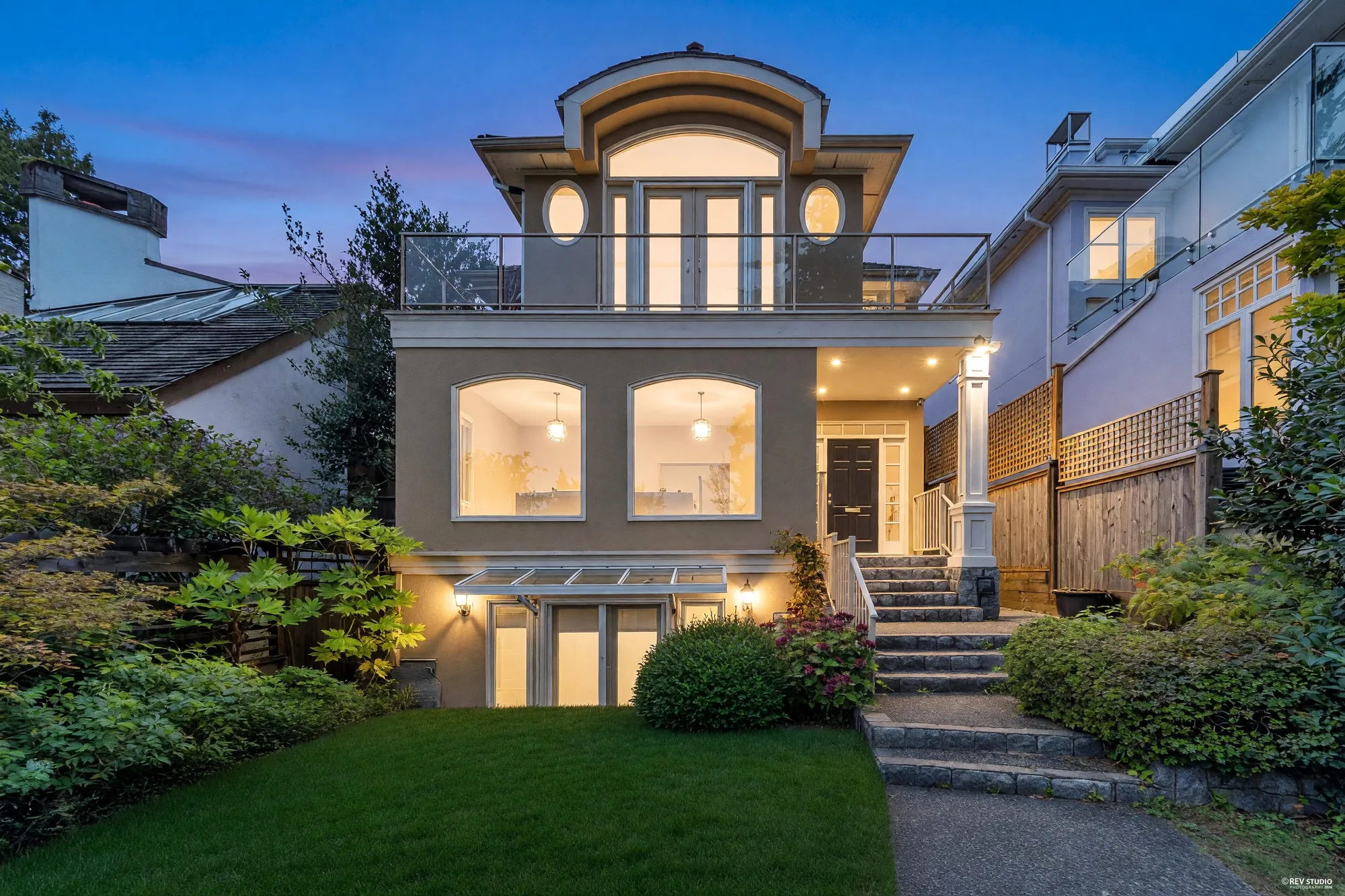 The front of the house at dusk with the windows lit