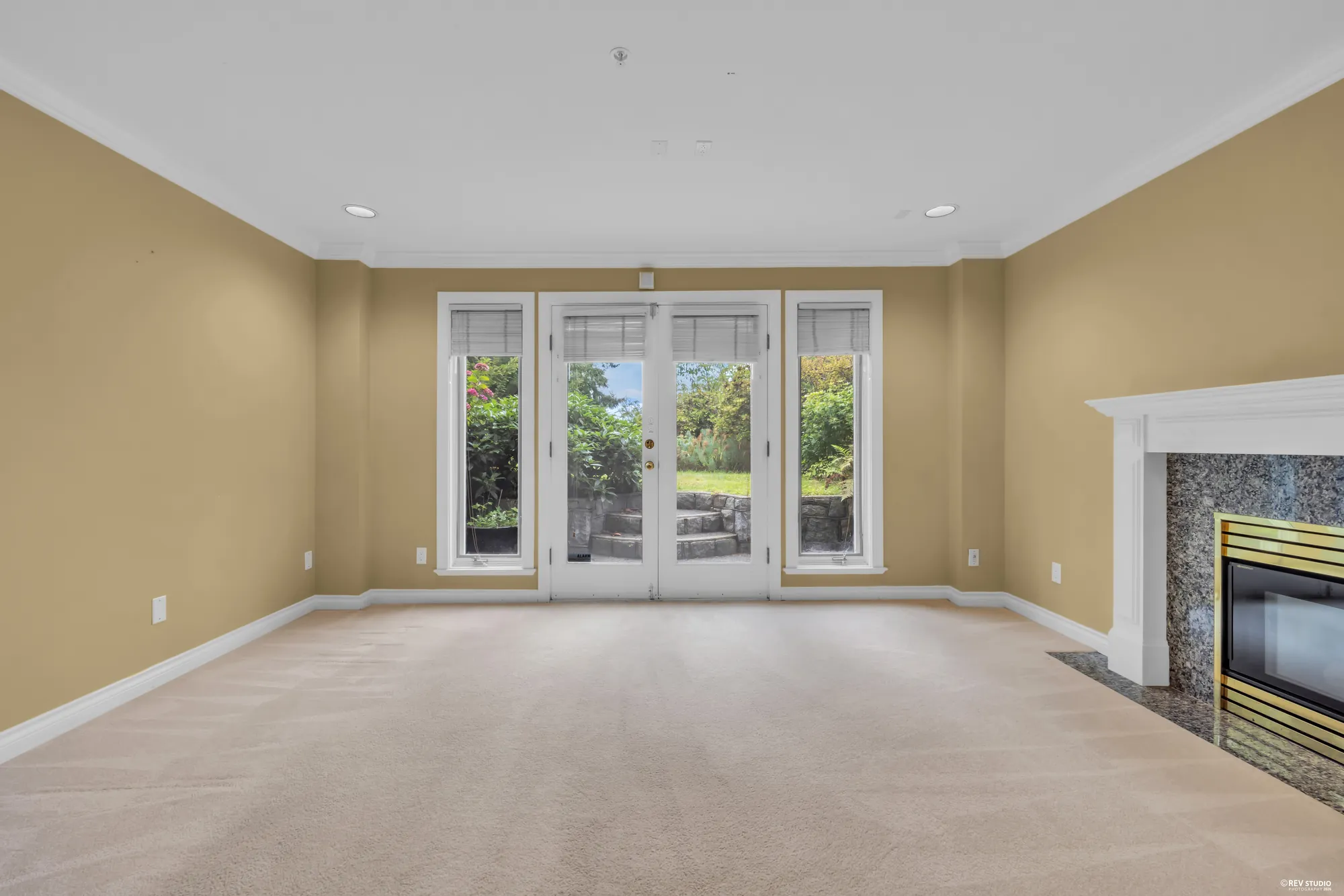 A carpeted lower room with French doors to the patio and a fireplace